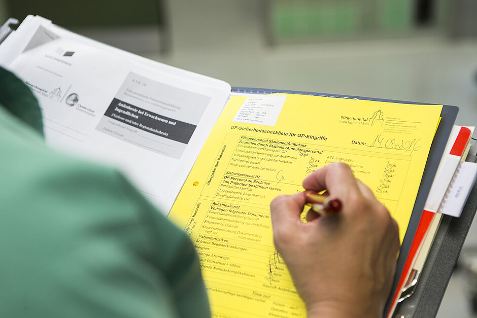Eine medizinische Fachkraft überprüft und füllt eine OP-Sicherheitscheckliste des Bürgerhospitals Frankfurt aus